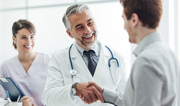 Doctor shaking hands with patient while nurse stands in background